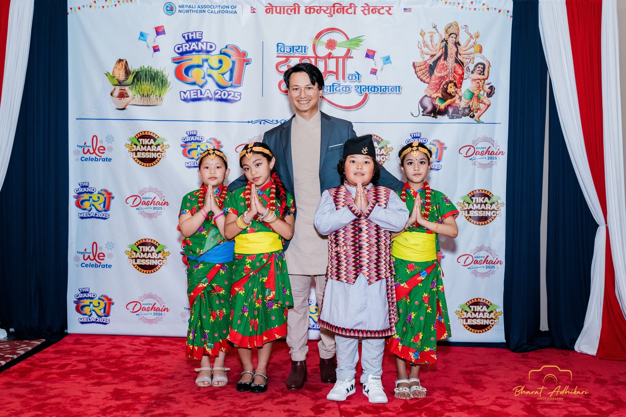 Children in traditional Nepali dress greeting with namaste at the photo booth