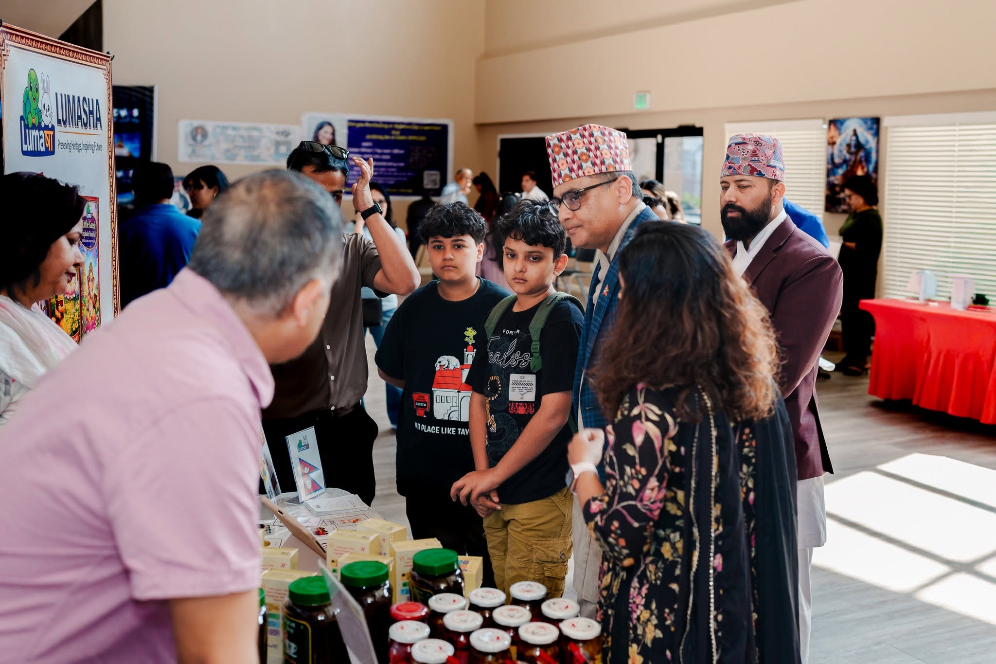 Families browsing a local business vendor booth at the Mela
