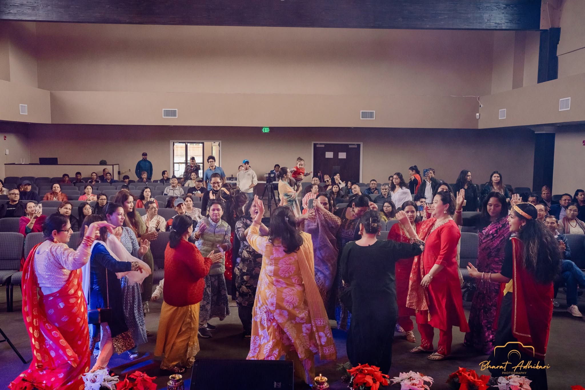 Women dancing together in a circle in the packed community hall
